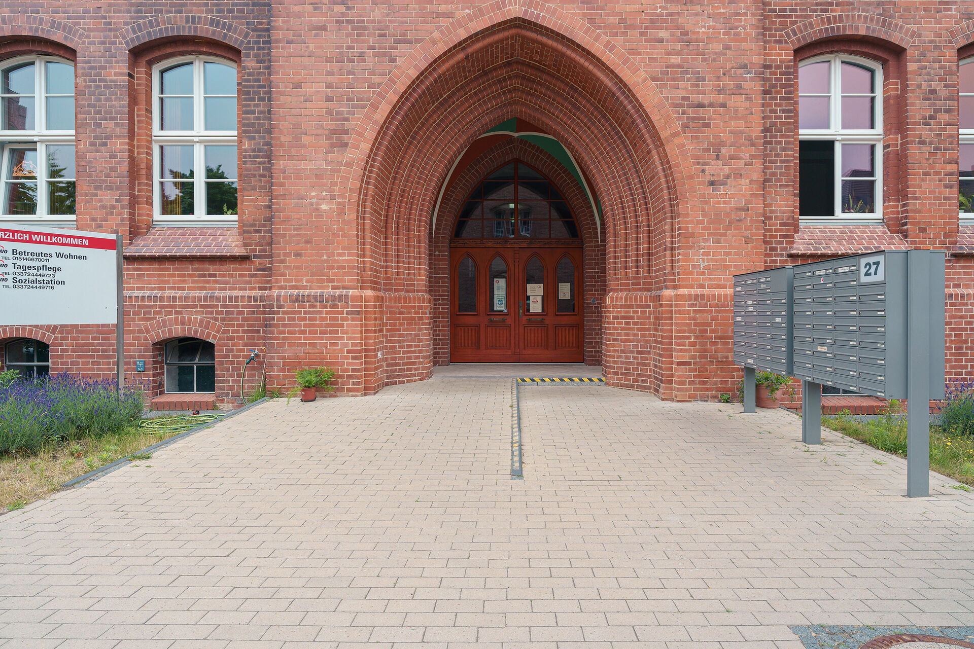 Großes historisches Gebäude, Eingang im Torbogen. Rechts davor Briefkästen.