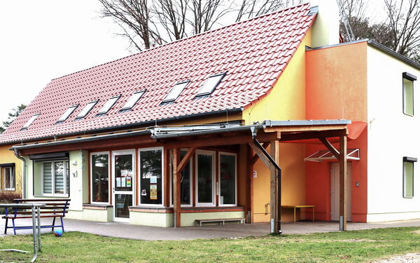 Kita Gebäude, davor eine Terrasse und Wiese.