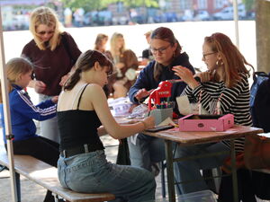 Kinder / Jugendliche sitzen am Tisch, basteln und malen.