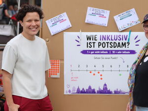 2 Frauen vor einer Stellwand mit Plakat. Die Frage: Wie inklusiv ist Potsdam?   Darunter ein Strahl von 1 bis 10.