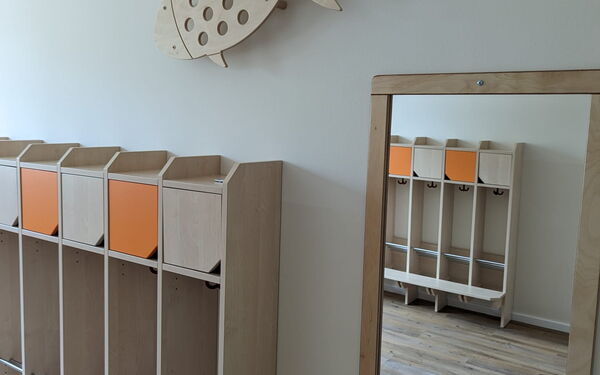 Kinder Garderabe, daneben ein Spiegel an der Wand.