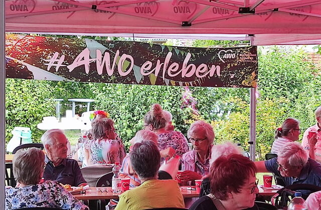 Draußen, Sonne scheint, Kaffeetafeln und größtenteils ältere Menschen die zusammensitzen.