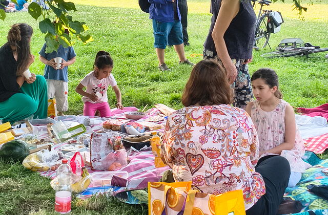Picknick. Erwachsene und Kinder auf Decken sitzend.