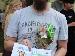 Mann mit rotem Base Cap und Vollbart hält Pokal und Urkunde zum 1. Platz in den Händen.
