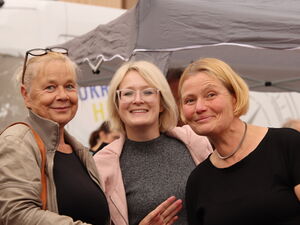 3 blonde Frauen stehen nebeneinander und lächeln in die Kamera.