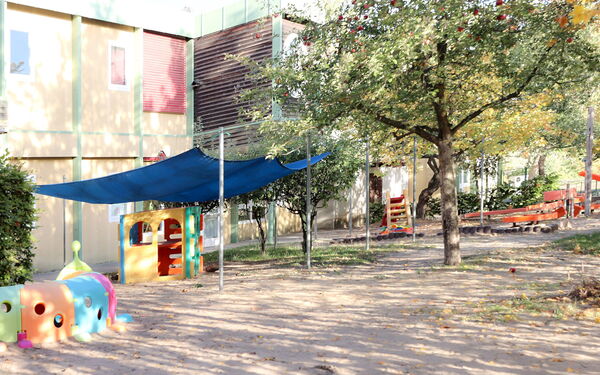 Spielplatz vor einem Kita Gebäude.