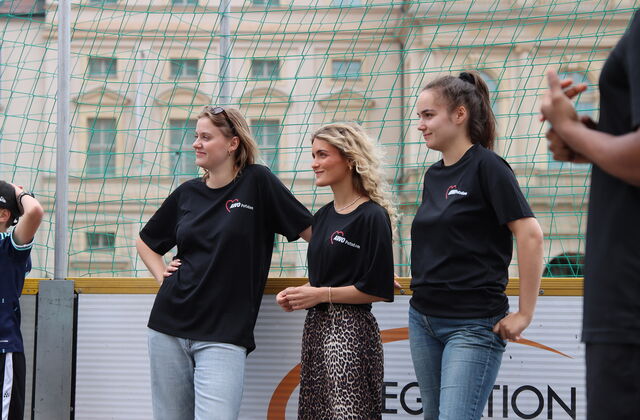 3 junge Frauen in dunklen AWO T-Shirts stehen am Netz.