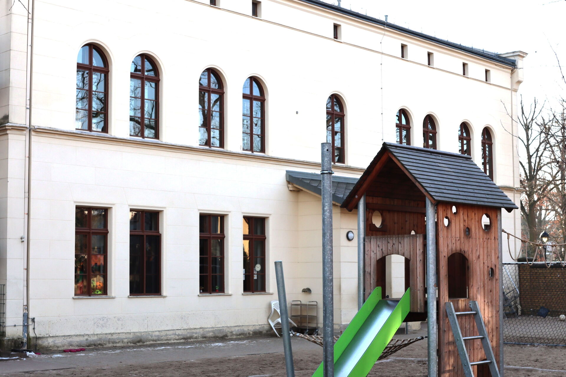 Ein kleines Klettergerüst mit Rutsche vor dem Kitagebäude.