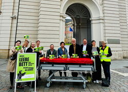 Mit leerem Pflegebett vor dem Landtag