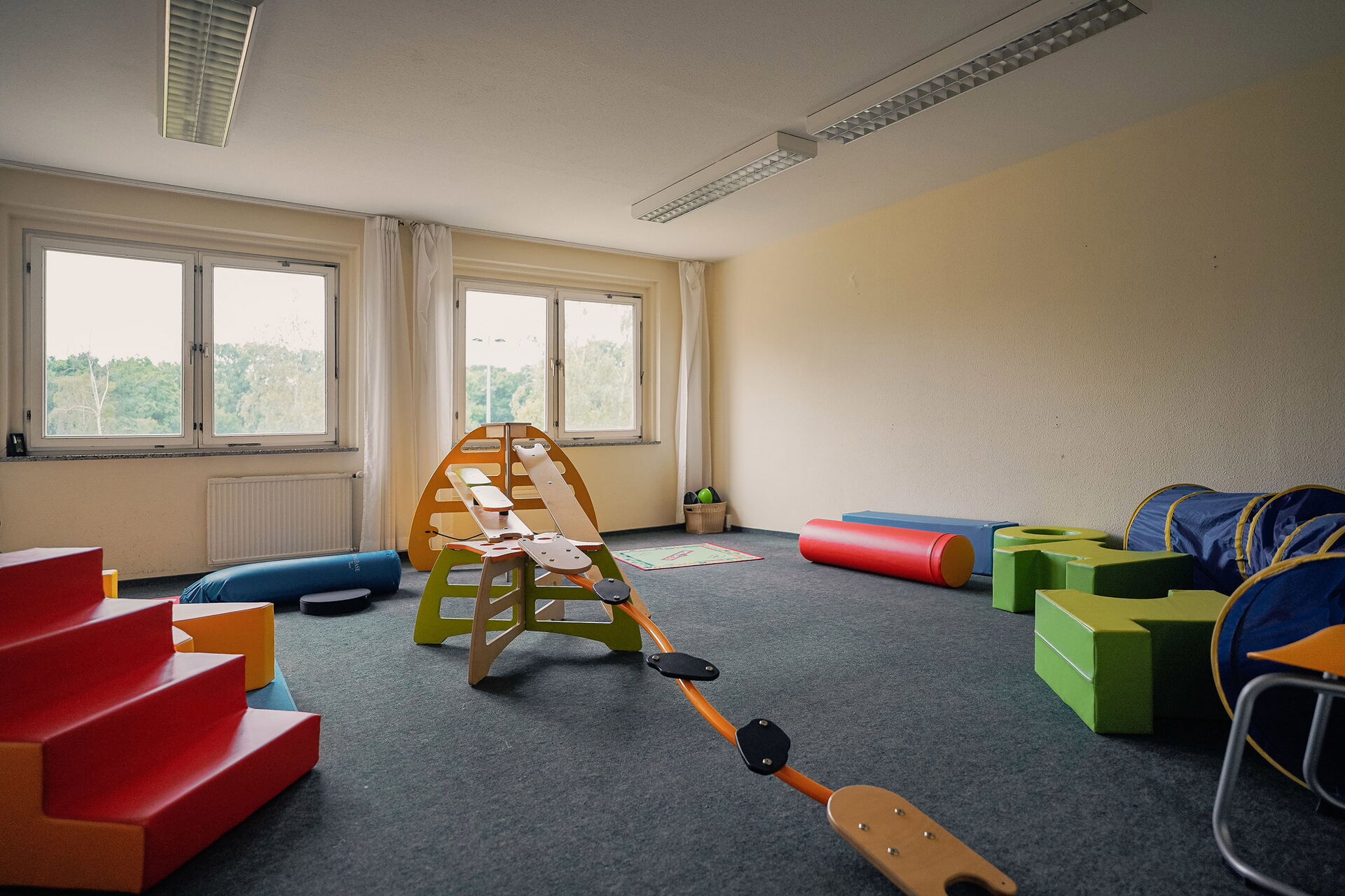 Großes Spielzimmer mit Geräten zum Balancieren und Kletter, eine rote Treppe.