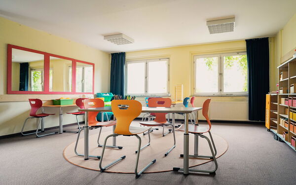 Großes helles Zimmer mit Tischen und Stühlen.