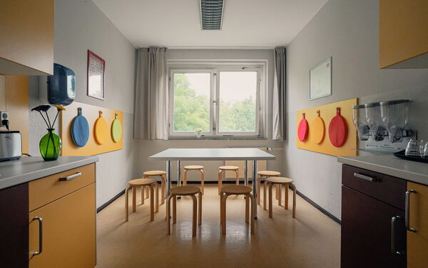 Küche mit großen Tisch mit 8 Hocker rings rum. Großes Fenster lässt Licht hinein.
