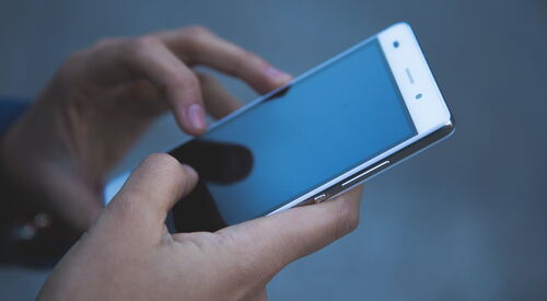 Ein Smartphone wird von zwei Händen gehalten.
