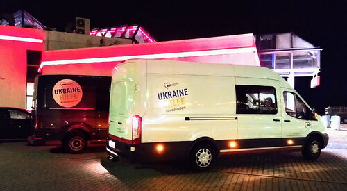 Zwei große Transporter mit Aufdruck "Ukrainehilfe" stehen auf einem Parkplatz bei Nacht.