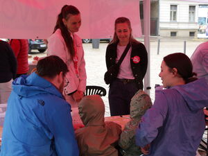 Menschen sitzen und stehen unter einem Pavillon.