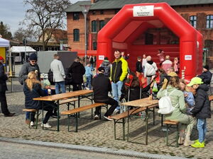 Rote Hüpfburg davor zwei Biertischgarnituren. Kinder beim Hüpfen.