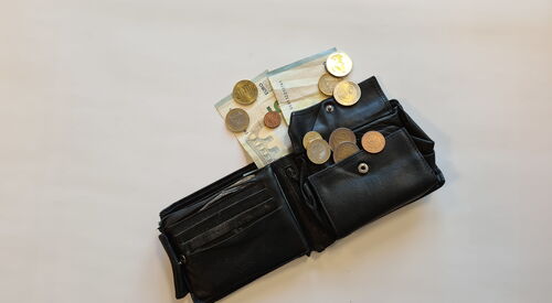 Ein aufgeklapptes Herren Portemonnaie. Geld Münzen und Scheine gucken raus.