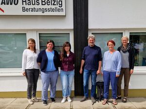 Gruppenbild. 5 Frauen und ein Mann vor einem Gebäude. Oben ein großes Schild am Gebäude angebracht. AWO-Logo        Haus Belzig Beratungsstelle