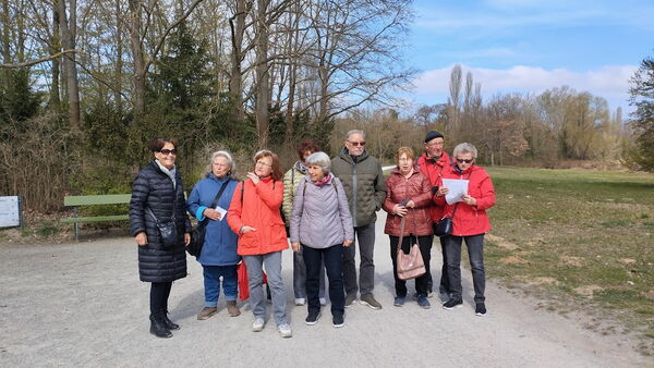 9 Personen stehen draußen in der Natur auf einen breiten Weg.