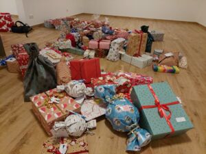 Viele in Geschenkpapier einpackte Weihnachtsgeschenke liegen auf dem Fußboden in einem leeren Raum.