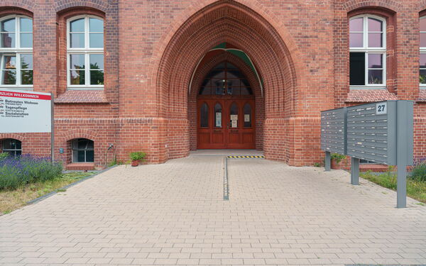 Großes historisches Gebäude, Eingang im Torbogen. Rechts davor Briefkästen.