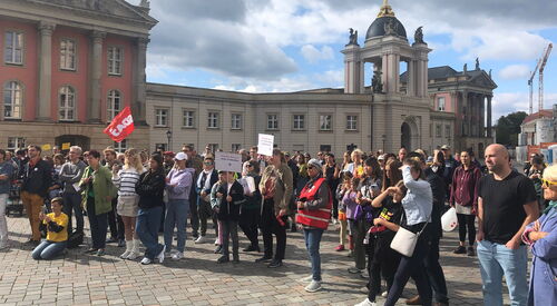 Demonstration. Viele Menschen mit Plakaten und Fahnen, stehen bei schönen Wetter auf dem Alten Markt.