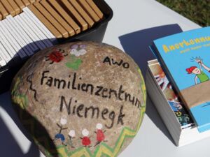 Ein großer bunt bemalter Stein: Blume, Marienkäfer, 4 Strichmännchen und dem Text:: AWO Familienzentrum Niemegk