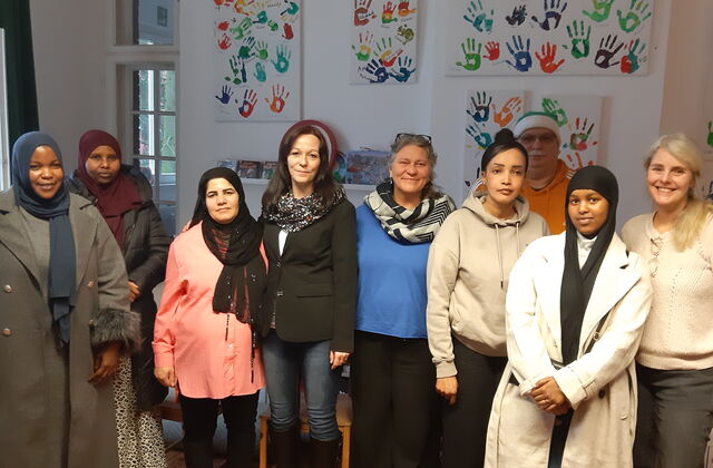 Christin Willnat, Bundestagsabgeordnete von den Linken und Thomas Lotsch vom Kreisverband der Linken im Havelland umringt von Mitarbeitern und Besucherinnen des interkulturellen Familiencafés