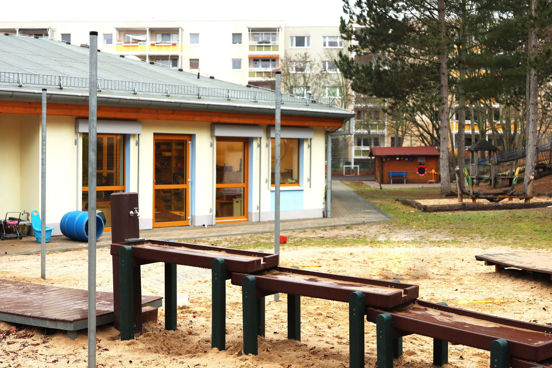 Kita Gebäude mit Spielplatz davor, Wasserspielplatz, Sandkasten.