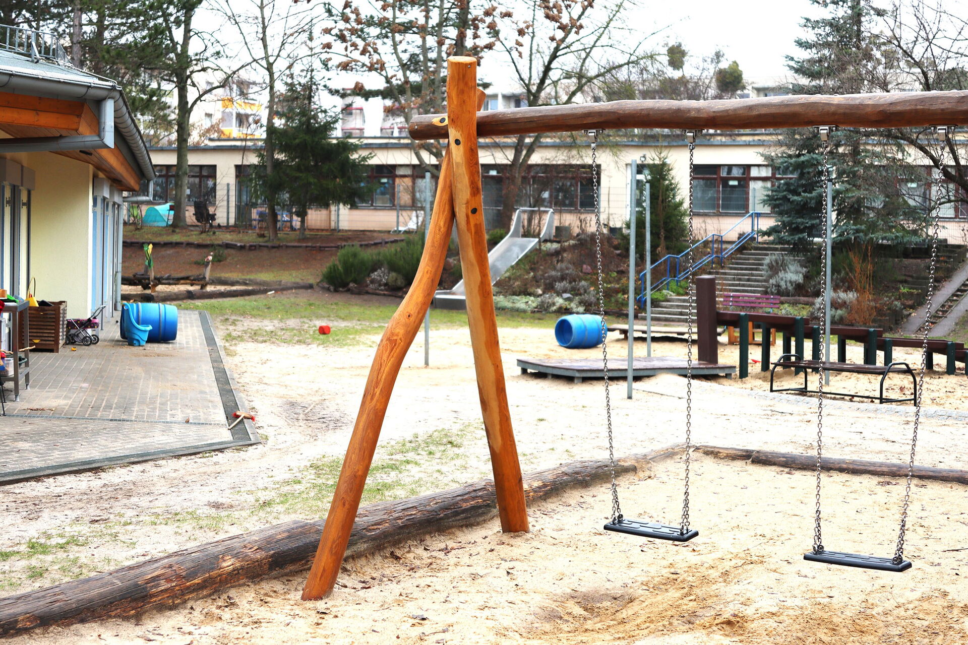 Spielplatz einer Kita. Zwei Schaukeln, weiter hinten eine Rutsche.
