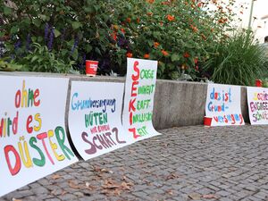 5 Große Plakate an einer niedriegenn Mauer angelehnt. Texte auf den Plakaten: 1. ohne wird es düster 2. Grundversorgung hüten wie einen Schatz 4. das ist Grundversorgung 5. Soziales Engagement schützen.