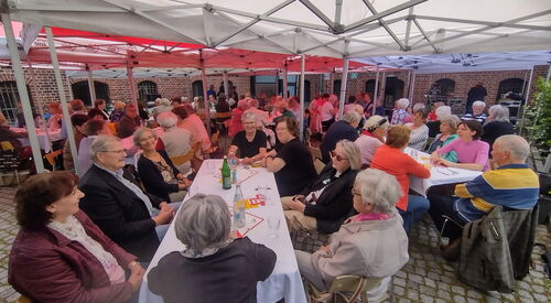 Festzelt, viele lange Tische. Viele Menschen sitzen an den Tischen. Größtenteils ältere Menschen.