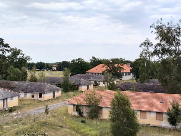 Aufnahme von Landschaft ind Flachbauten. Häuser wirken alt, Fenster mit Brettern abgedichtet stehen akurat aufgereit.