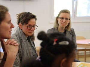 3 Frauen sitzen um einen Tisch.