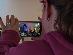 Eine Frau hält ein Smartphone hoch und filmt damit das Kulturprogramm.