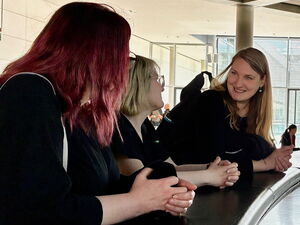 Glaskuppel Bundestag von innen. 3 Frauen stehen an der Brüstung die Einblick zum Plenarsaal gibt.