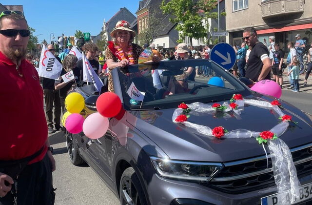 Geschmücktes Cabrio mit Luftballons und AWO Fahnen. Viele Menschen auf der Straße.