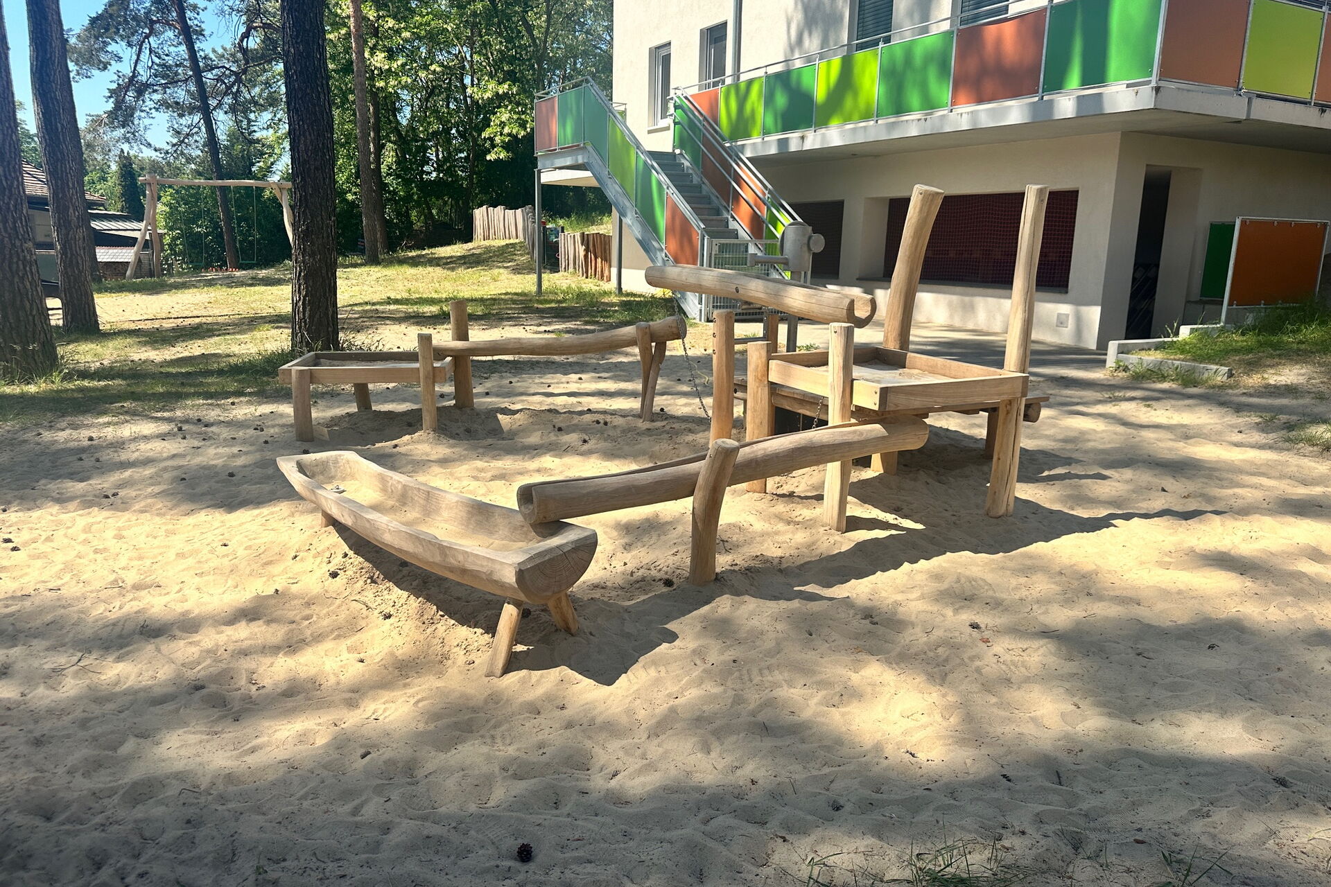 Wassermatschanlage. Eine Wasserpumpe Rohre und Wasserauffangbecken sind miteinander verknüpft. Aus Holz.