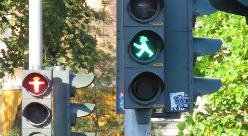 2 Fußgängerampeln, die hintere auf rot, die fordere auf grün. Ampelmännchen.