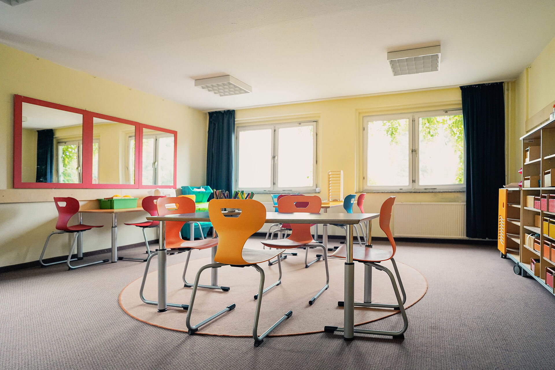 Großes helles Zimmer mit Tischen und Stühlen.
