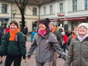 3 Frauen lachen und bewegen sich. Protestveranstaltung auf einem Platz.