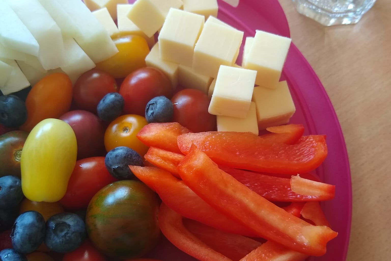 Ein bunter Teller mit Obst, Gemüse und Käsewürfeln