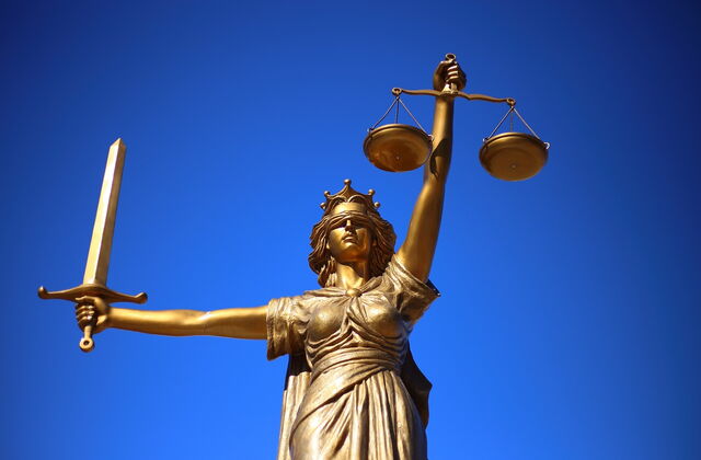Justicia Skulptur. Weiblich mit Wage in der linken Hand, Schwert in der rechten Hand und Augenbinde.