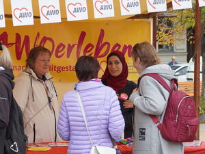 AWO erleben Stand mit gelben Banner. Menschen beraten interessierte Ehrenamtssuchende.