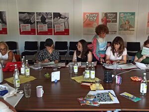 Großer Raum, großer Tisch. Frauen sitzen am Tisch, sehen sich Stadtpläne an.