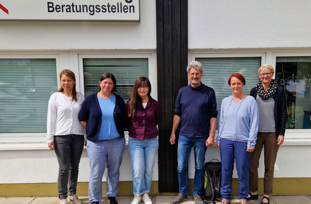 Gruppenbild. 5 Frauen und ein Mann vor einem Gebäude. Oben ein großes Schild am Gebäude angebracht. AWO-Logo        Haus Belzig Beratungsstelle