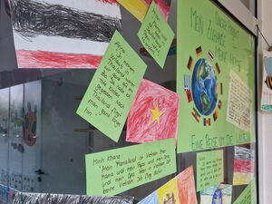 Glasscheibe. Dort sind gemalte Länder-Flaggen und Zitate von Kindern.