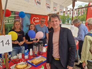 Stand der AWO Ehrenamtsagentur mit Kaffee und Kuchen. Vor dem Stand steht ein Mann und lächelt in die Kamera.