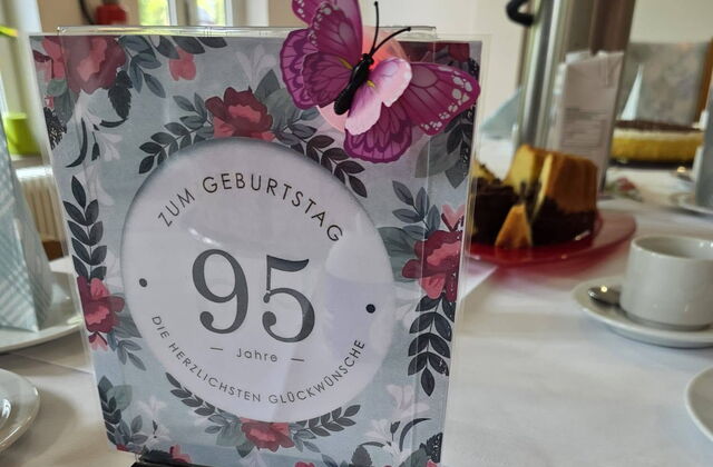 Gedeckter Kaffeetisch. Nahaufnahme einer Karte zum 95. Geburtstag.