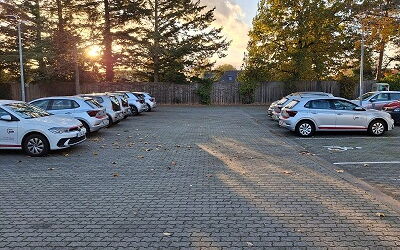 gepflasterte große Parkfläche, links vom Bild stehen 6 Autos der AWO hintereinander, rechts vom Bild 3 Autos der AWO und einem barrierefreiem Parkplatz